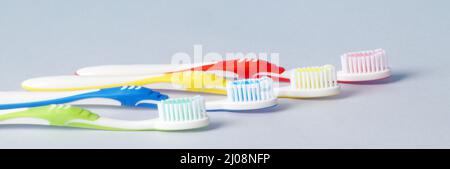 multi-colored toothbrushes are laid out one after another on the table Stock Photo