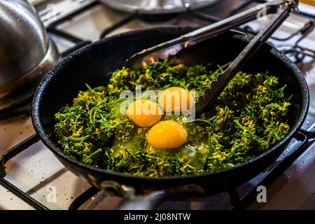Three eggs are fried in a pan with green vegetables, İsimsiz Yol, Büyükkonuk, TRNC Stock Photo