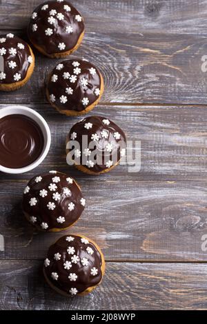 Spicy pumpkin muffins with nuts, decorated with chocolate glaze and sugar snowflakes under the Christmas tree on a wooden table, free space, selective Stock Photo