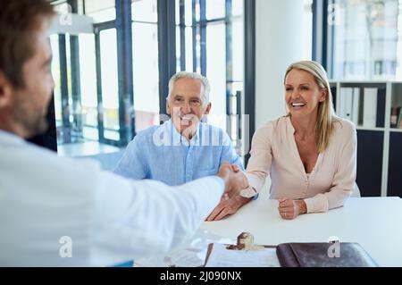 The doc has some good news for them. Shot of a doctor meeting up with a senior patient and his daughter for consultation in a clinic. Stock Photo