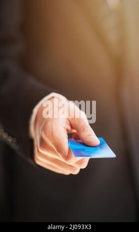 Paying by card. Cropped shot of a businessman holding out a credit card as payment. Stock Photo