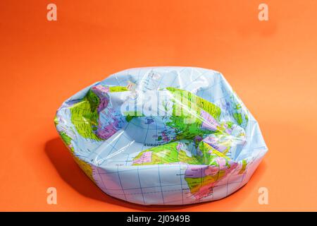 Deflated globe isolated on orange background. Stock Photo