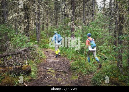 Hikers and tourists walk along a muddy trail soaked after heavy rain Stock Photo