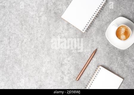Workspace top view with notepads, pen and coffee with milk on grey stone background. Flat lay with copy space. Business concept. Stock Photo