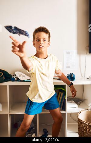 Letting his imagination soar. Portrait of a little boy flying a paper jet at home. Stock Photo