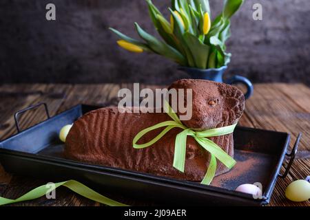 Classic chocolate Easter lamb pound cake sprinkled with cocoa powder on wooden background Stock Photo