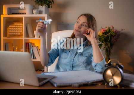 Beautiful smiling woman working at her workplace in the office and dreams about travel. Concept of lovely job. Stock Photo