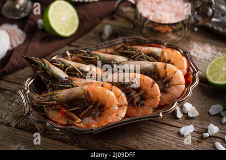 The dish with tiger shrimps on rustic wooden table with assorted seafood background. Delicious meal. Concept of healthy food. Stock Photo