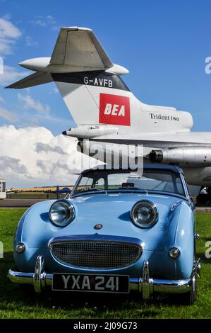 Vintage Austin Healey Sprite Mark I classic car, with old Hawker Siddeley Trident 2 airliner jet plane in vintage BEA colours. Nostalgia, old times Stock Photo