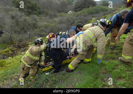 San Diego Fire-Rescue firefighters from Stations 20 and 36 performing a technical rescue of a driver on an over-the-side, off-the-road accident. Stock Photo