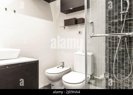 Bathroom with shower cabin with glass partition, angular white porcelain sink and black and gray marble tiled tiles Stock Photo