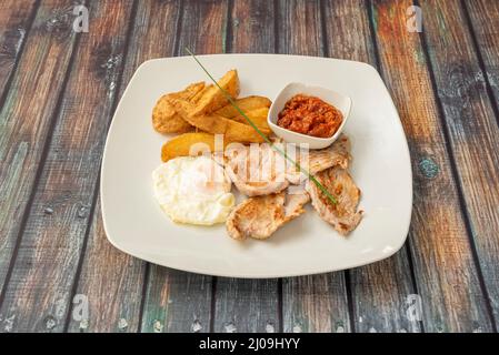 Grilled Pork Tenderloin Combo Plate with Fried Egg, Home Fries and Tomato Paste Stock Photo