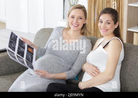 two pregnant women looking at print out of ultrasound scan Stock Photo