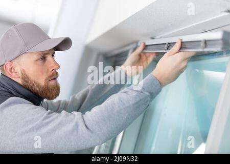 man installing cassette roller blinds on windows Stock Photo