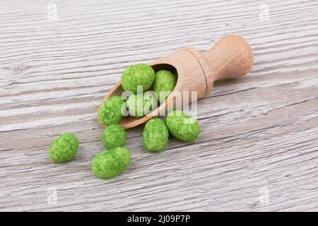 Wasabi coated peanuts on wooden background Stock Photo
