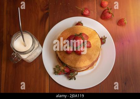 Plate of hot cakes and strawberries on a wood table Stock Photo