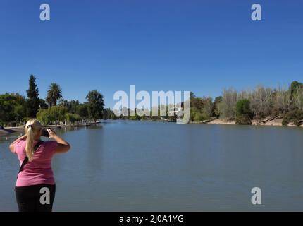 Blonde woman taking a picture in a lake. Stock Photo