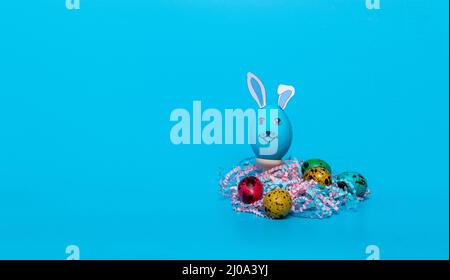 blue Easter egg with ears and colored quail eggs Stock Photo
