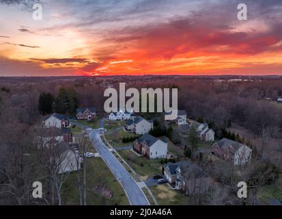 Curving road leading to a dead end neighborhood with colorful orange evening sun is setting over upper class East Coast American neighborhood cul-de-s Stock Photo