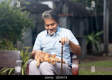 Senior asian man holding ginger cat in backyard Stock Photo