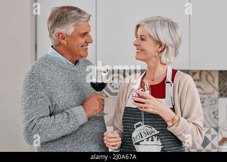 Celebrate the simple moments. Shot of a happy mature couple having red wine together while cooking at home. Stock Photo