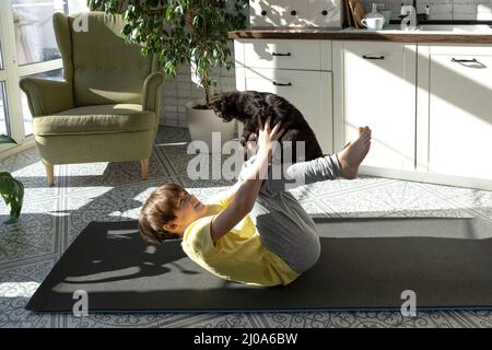 Little boy practicing yoga, stretching, fitness at home. Distant online education training, aerobic at home. Healthy lifestyle, coronavirus, stay home Stock Photo