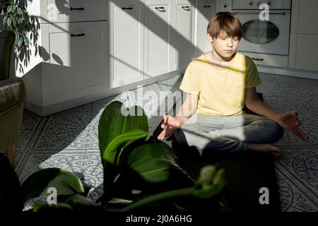 Little boy practicing yoga, stretching, fitness at home. Distant online education training, aerobic at home. Healthy lifestyle, coronavirus, stay home Stock Photo