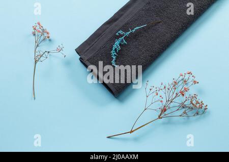 Soft terry towel with decorative branches on the blue background. Spa products. Top view. Stock Photo