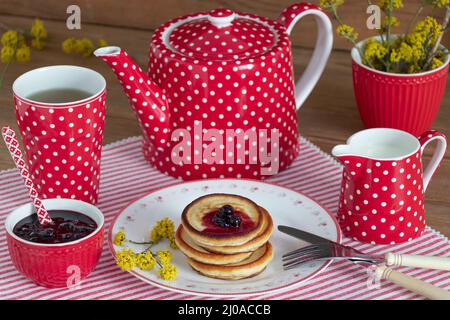 pancakes with currant jam on plate and red tea set Stock Photo