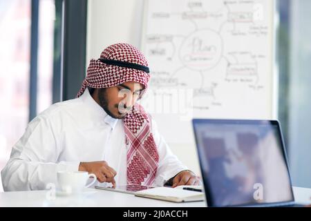 Staying on task with smart technology. Shot of a young muslim businessman using a digital tablet at his work desk. Stock Photo