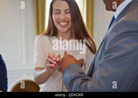 Mixed race black and white interracial couple holding hands and exchanging vows and wedding rings at wedding ceremony. Multiracial family Stock Photo