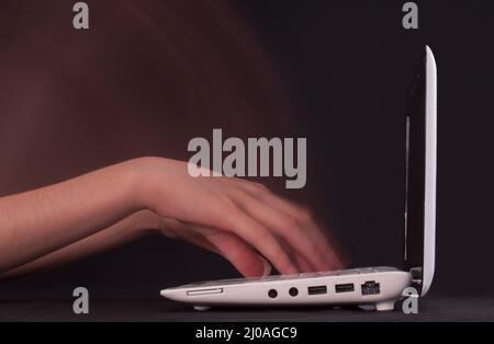 Hands typing in motion on the laptop keyboard Stock Photo