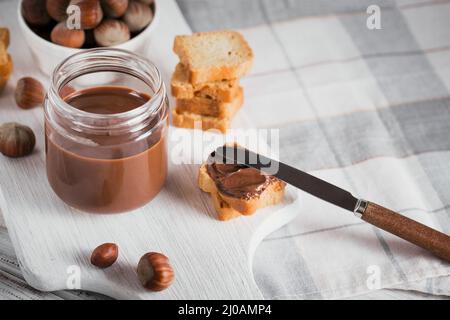 Little Toasts with sweet hazelnut chocolate spread for breakfast on white wooden background Stock Photo