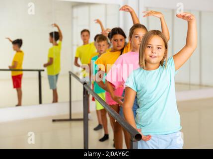 Children standing along ballet bar in dance studio during dance class Stock Photo