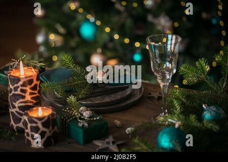 Christmas table setting with empty black ceramic plate, fir tree branches and green gift boxes on dark wooden background Stock Photo