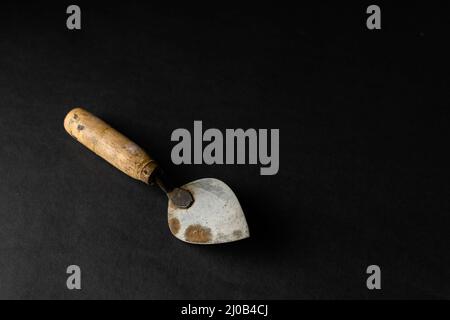 Trowel on black background with copy space and used selective focus. This hand trowel used in brickwork or stonework for leveling, spreading and shapi Stock Photo