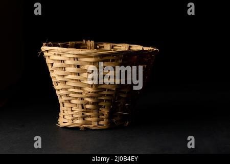 Small bamboo basket to make bouquet of flower. Handmade for kept flowers used as a bouquet base. Isolated in black background with selective focus use Stock Photo