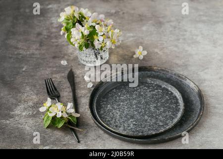 Spring place table setting with blossoming apple tree branches and flowers on grey table. Holidays decoration on Provence style. Romantic dinner. Over Stock Photo