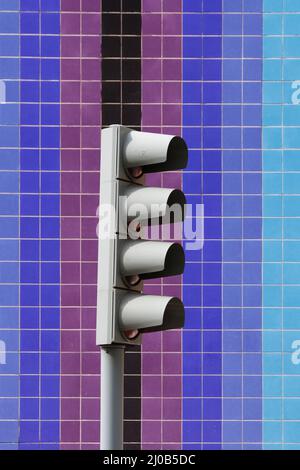 regular square wall tiles in shades of yellow orange beige red and blue with a four light traffic mechanism including filter lane Stock Photo