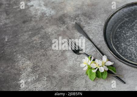 Spring place table setting with blossoming apple tree branches and flowers on grey table. Holidays decoration on Provence style. Romantic dinner. Over Stock Photo