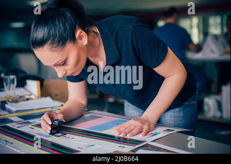 Worker in a printing and press centar uses a magnifying glass and check the print quality Stock Photo