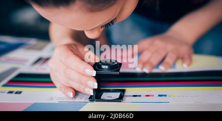 Worker in a printing and press centar uses a magnifying glass and check the print quality Stock Photo