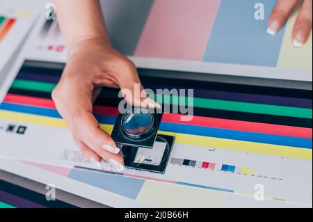 Worker in a printing and press centar uses a magnifying glass and check the print quality Stock Photo
