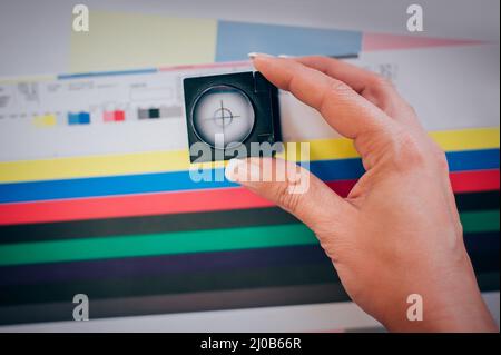 Worker in a printing and press centar uses a magnifying glass and check the print quality Stock Photo