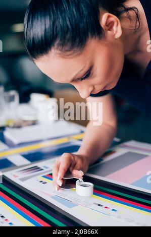 Worker in a printing and press centar uses a magnifying glass and check the print quality Stock Photo