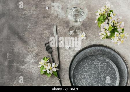 Spring place table setting with blossoming apple tree branches and flowers on grey table. Holidays decoration on Provence style. Romantic dinner. Over Stock Photo