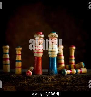 Wooden sailors figurines stand together with scattered pegs on a rustic surface during an indoor gathering Stock Photo