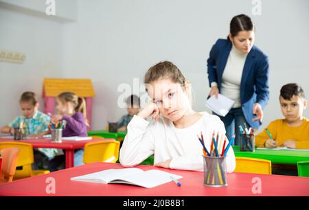 Portrait of tired schoolgirl sitting in classroom elementary school Stock Photo