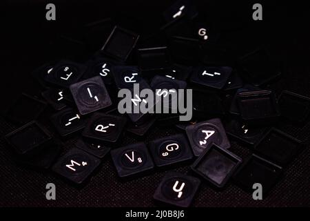 Scattered keyboard letter keys isolated on black background Stock Photo