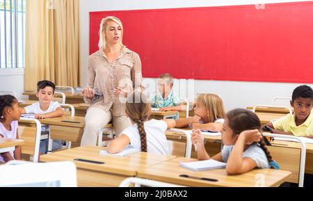 Woman teacher helping preteen schoolchildren during lesson Stock Photo